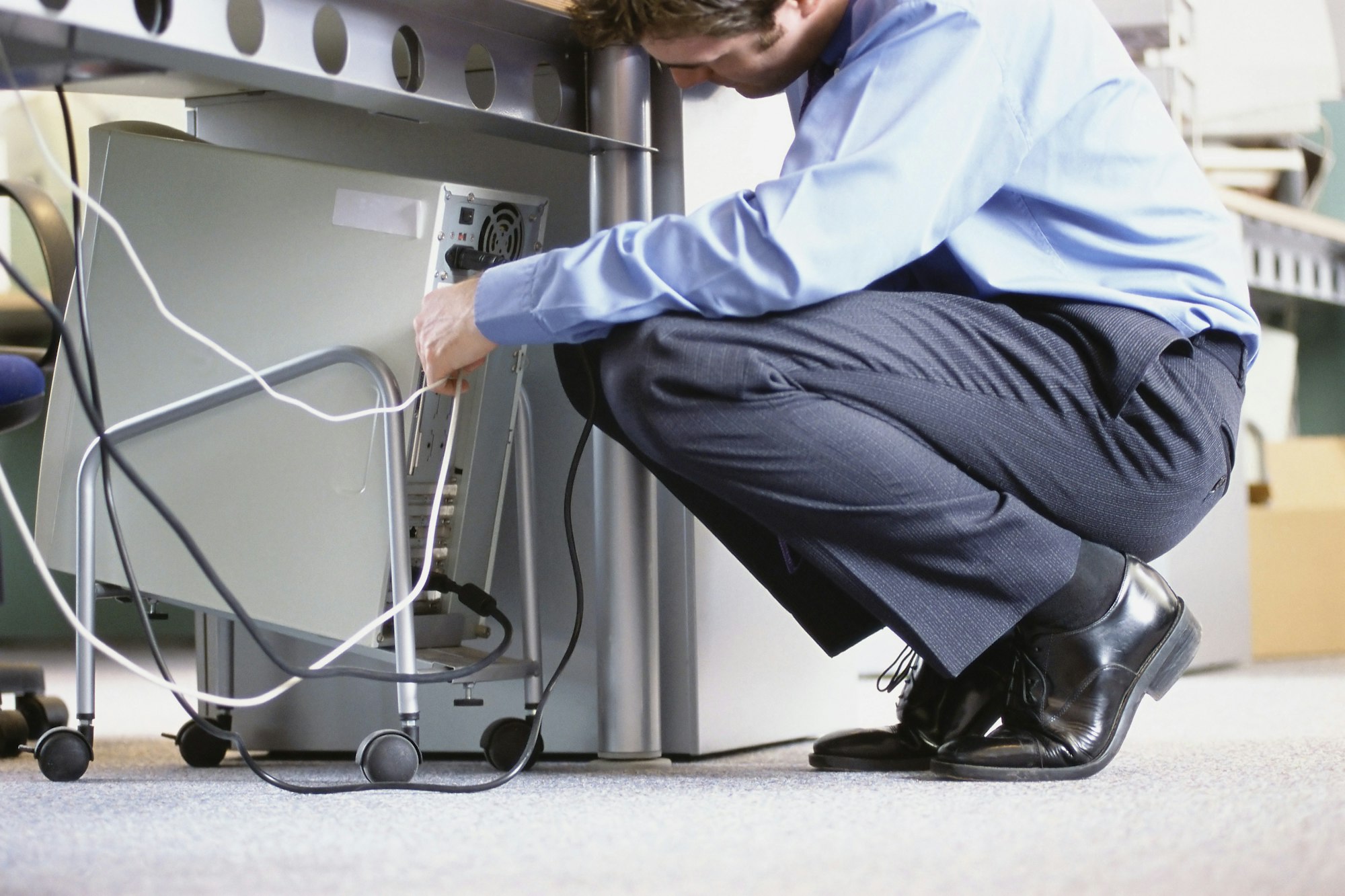 Caucasian businessman connecting cables to computer in office